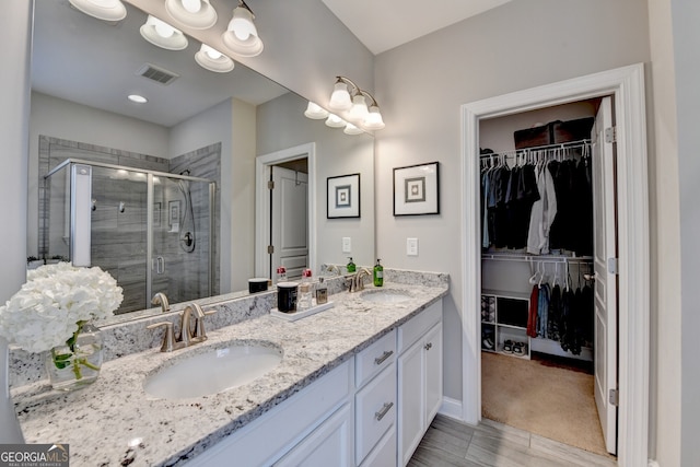 full bathroom with double vanity, visible vents, a sink, and a shower stall
