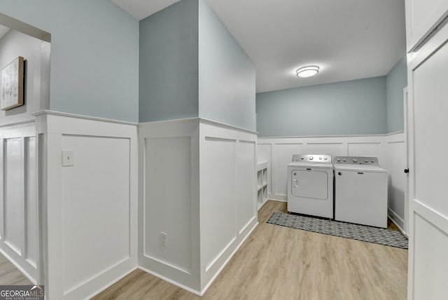 washroom with washer and clothes dryer, wainscoting, laundry area, and light wood finished floors