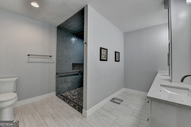 full bathroom featuring toilet, a walk in shower, baseboards, and a sink