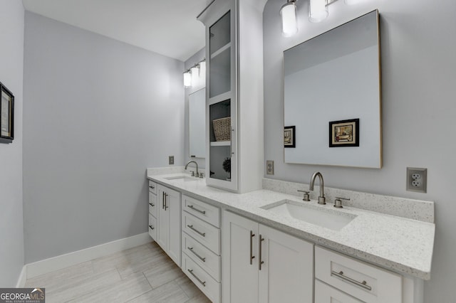 bathroom with double vanity, baseboards, and a sink