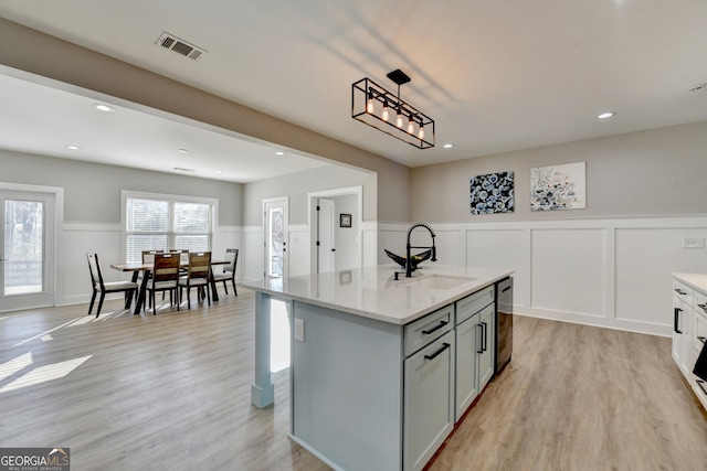 kitchen featuring stainless steel dishwasher, light wood-style floors, visible vents, and a sink