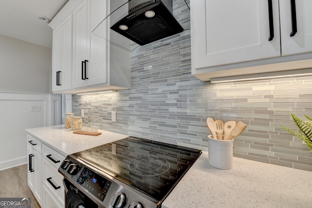 kitchen featuring range hood, white cabinetry, stainless steel range with electric cooktop, light stone countertops, and decorative backsplash