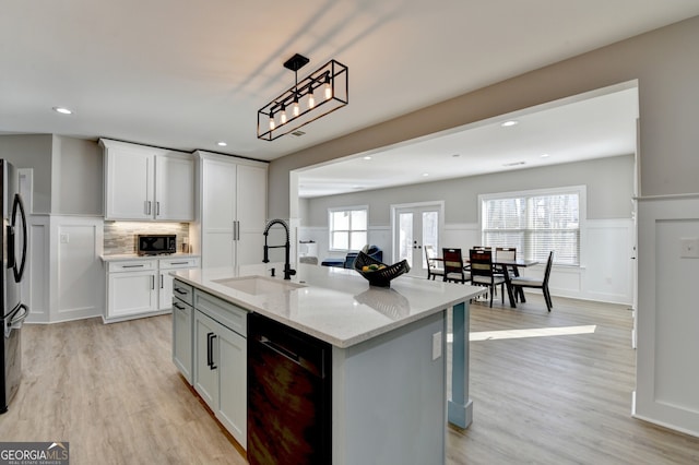 kitchen featuring black appliances, light wood-style flooring, light stone countertops, and a sink