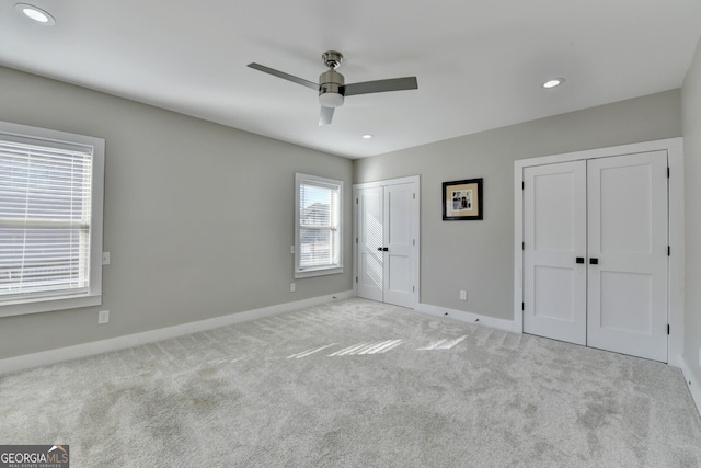 unfurnished bedroom featuring recessed lighting, baseboards, light carpet, and two closets