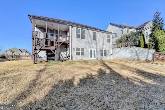 rear view of house featuring a lawn, a wooden deck, fence, and stairway