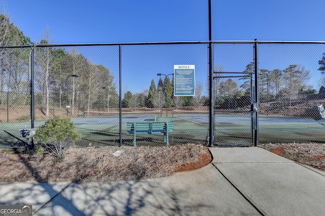 view of tennis court featuring a gate and fence