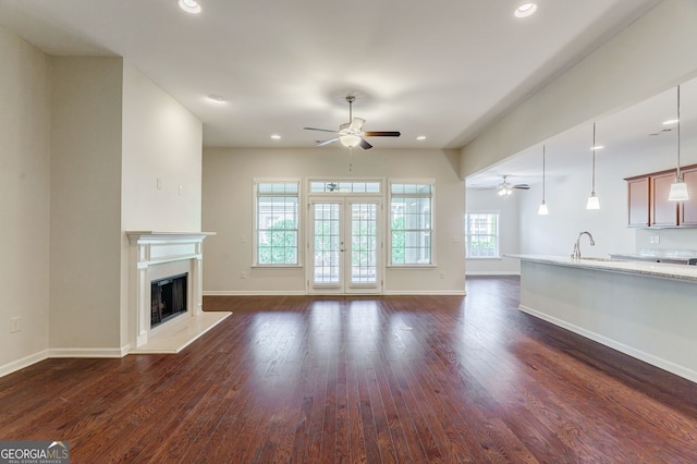 unfurnished living room featuring dark wood-style floors, recessed lighting, a fireplace with raised hearth, and a ceiling fan