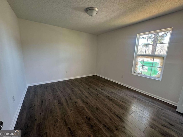 spare room featuring baseboards, a textured ceiling, and dark wood-style floors