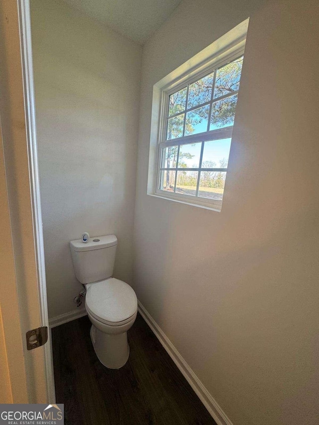 bathroom with toilet, baseboards, and wood finished floors