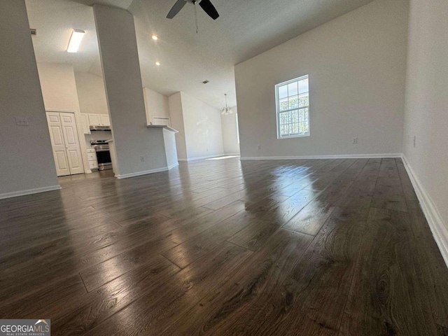 unfurnished living room featuring dark wood-type flooring, ceiling fan with notable chandelier, baseboards, and high vaulted ceiling