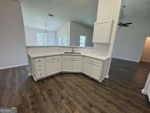 kitchen with dark wood-type flooring, white cabinets, tasteful backsplash, and a sink