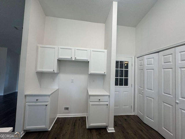 kitchen with tasteful backsplash, light countertops, a towering ceiling, white cabinets, and dark wood-style flooring