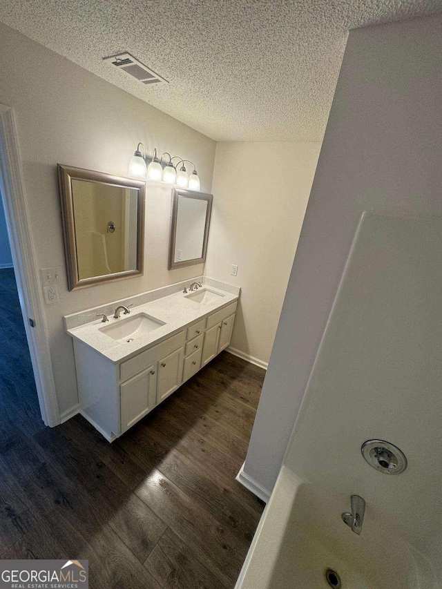 bathroom with a sink, visible vents, a textured ceiling, and wood finished floors