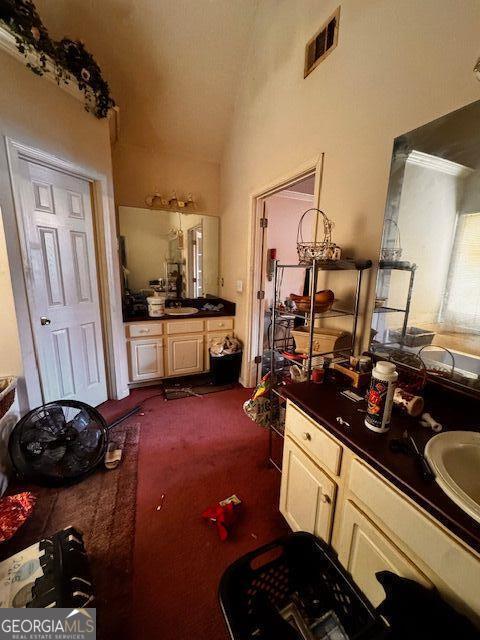 bathroom featuring visible vents, lofted ceiling, and vanity