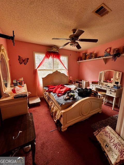 carpeted bedroom with ceiling fan, visible vents, and a textured ceiling