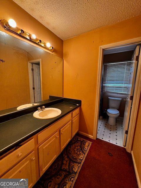 bathroom featuring a textured ceiling, toilet, vanity, and baseboards