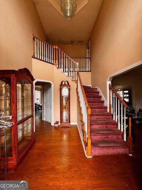 stairway with a high ceiling, wood finished floors, arched walkways, and french doors