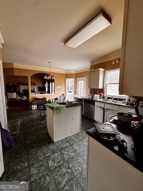 kitchen featuring ornamental molding, a sink, stainless steel dishwasher, dark countertops, and a center island