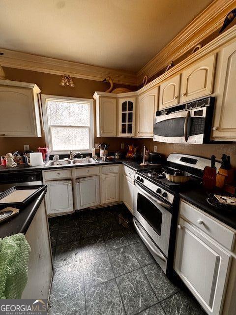 kitchen with dark countertops, gas stove, glass insert cabinets, and ornamental molding