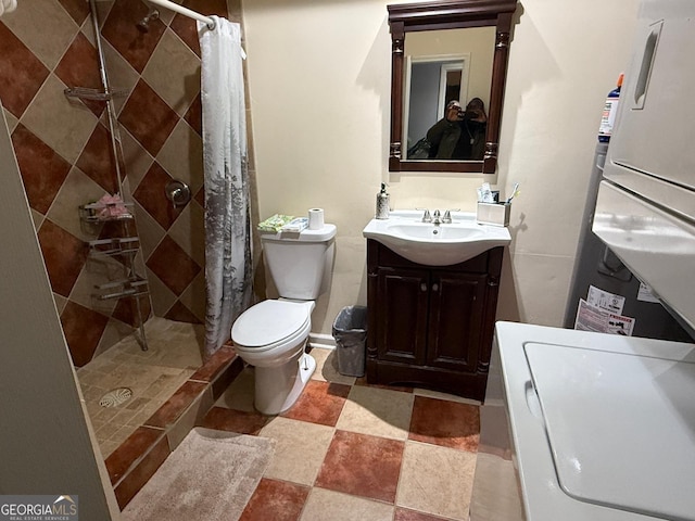 bathroom featuring vanity, washer / dryer, toilet, and tiled shower