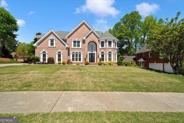 colonial inspired home with brick siding and a front lawn