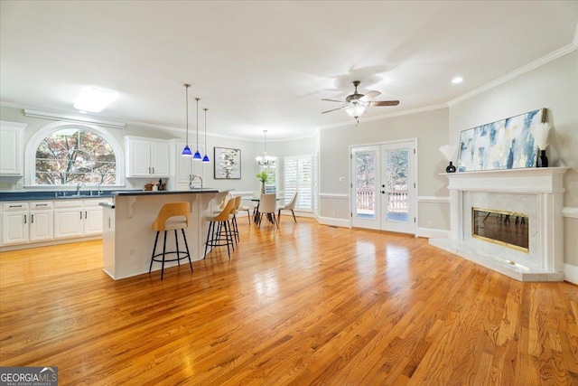 kitchen featuring dark countertops, a kitchen breakfast bar, light wood-style floors, white cabinetry, and ornamental molding