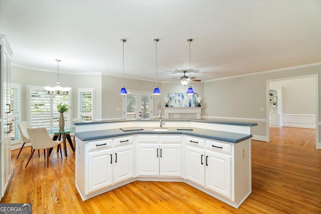 kitchen featuring dark countertops, decorative light fixtures, a center island with sink, and ceiling fan with notable chandelier