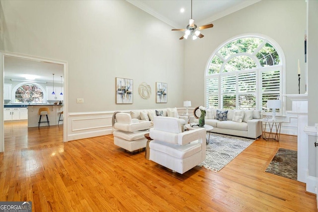 living room featuring high vaulted ceiling, ceiling fan, a healthy amount of sunlight, light wood-style flooring, and ornamental molding