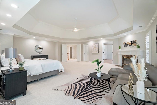 carpeted bedroom with a tray ceiling, a fireplace, crown molding, and recessed lighting