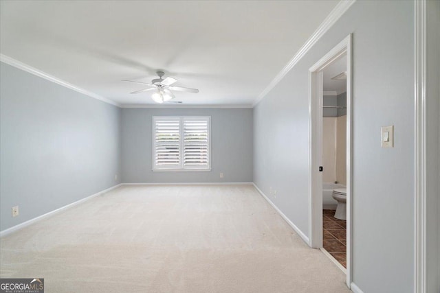 spare room with light colored carpet, ceiling fan, baseboards, and ornamental molding