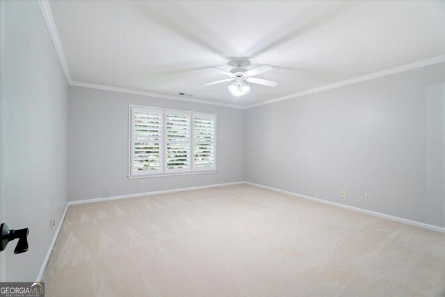 spare room with light carpet, crown molding, baseboards, and ceiling fan