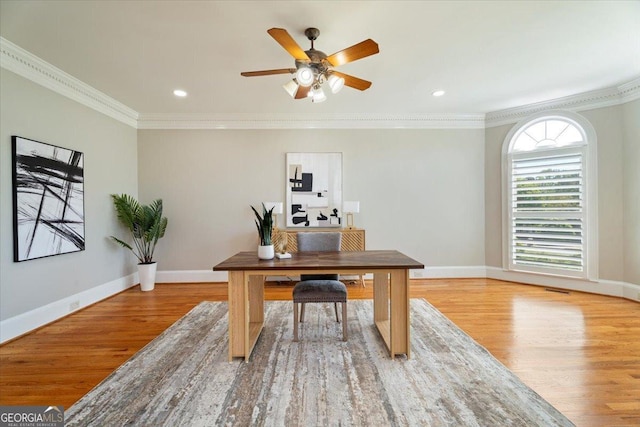 office space featuring baseboards, a ceiling fan, wood finished floors, and crown molding