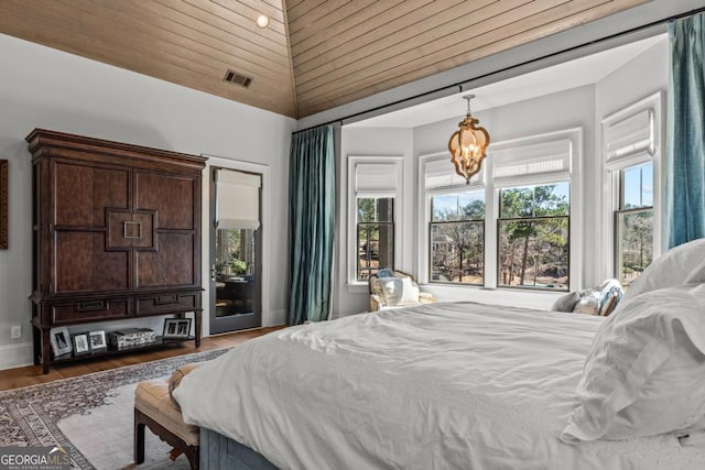 bedroom with a notable chandelier, visible vents, baseboards, and wood finished floors