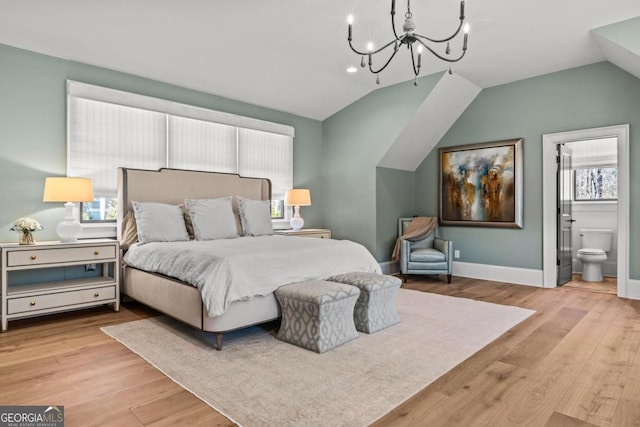bedroom with vaulted ceiling, wood finished floors, baseboards, and connected bathroom