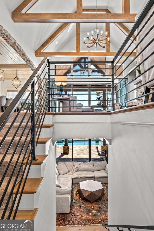 living area with stairs, beam ceiling, high vaulted ceiling, and a chandelier