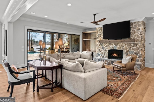 living area featuring baseboards, light wood-style flooring, recessed lighting, a fireplace, and ornamental molding
