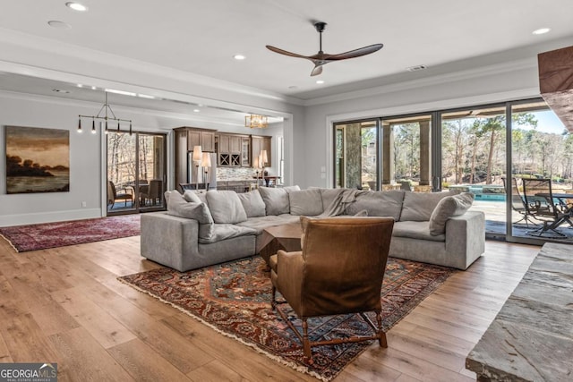 living area with light wood-style flooring, recessed lighting, visible vents, and ornamental molding
