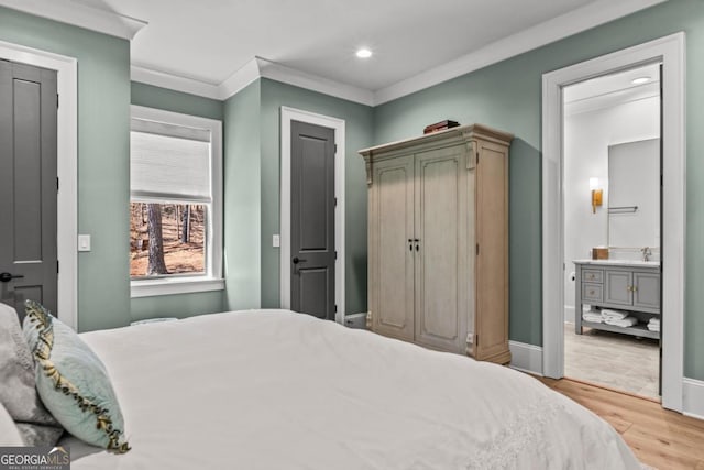bedroom featuring ornamental molding, a sink, wood finished floors, recessed lighting, and baseboards