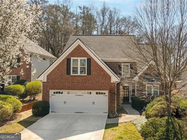 traditional home featuring brick siding, an attached garage, driveway, and a shingled roof