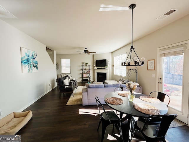 dining area featuring visible vents, baseboards, ceiling fan, a fireplace, and dark wood-style flooring