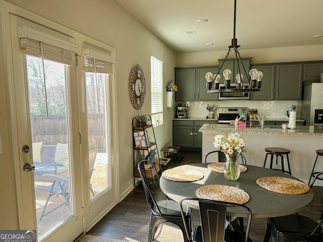 dining space featuring an inviting chandelier, visible vents, dark wood-style flooring, and baseboards