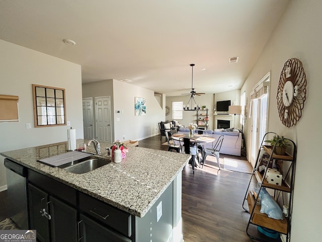 kitchen with visible vents, a fireplace, a sink, dishwasher, and open floor plan