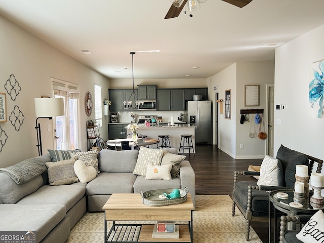 living room featuring dark wood finished floors, baseboards, and ceiling fan