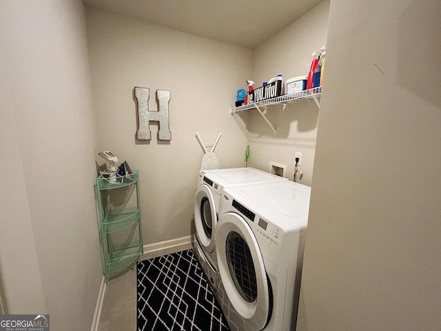 washroom with baseboards, independent washer and dryer, and laundry area