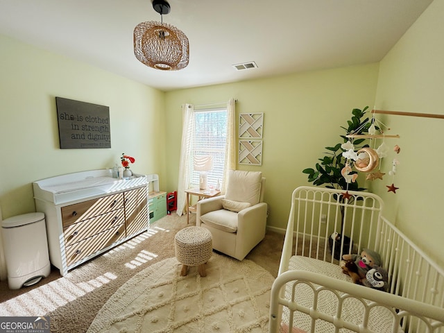 bedroom featuring a crib, carpet flooring, and visible vents