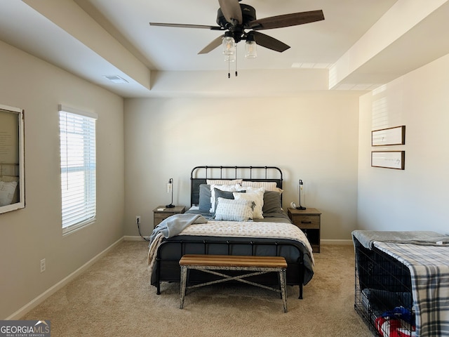 bedroom with light colored carpet, baseboards, and a tray ceiling