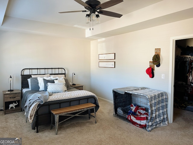 carpeted bedroom featuring a walk in closet, a closet, and a ceiling fan