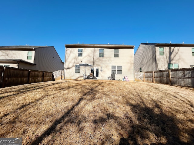 back of property featuring a lawn and a fenced backyard