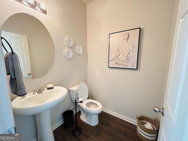 bathroom with toilet, baseboards, and wood finished floors