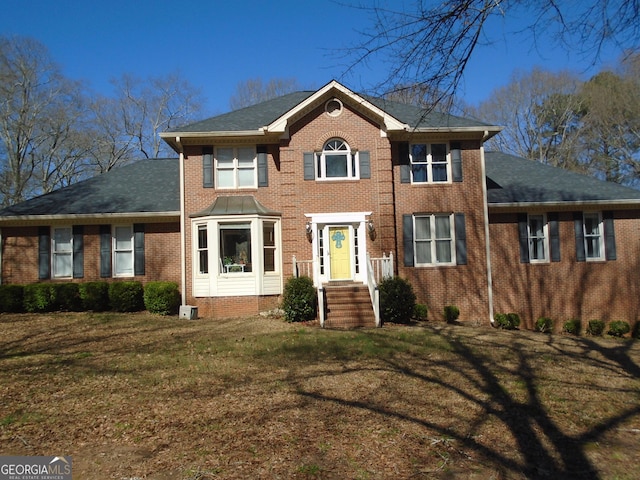 colonial house with a front yard and brick siding